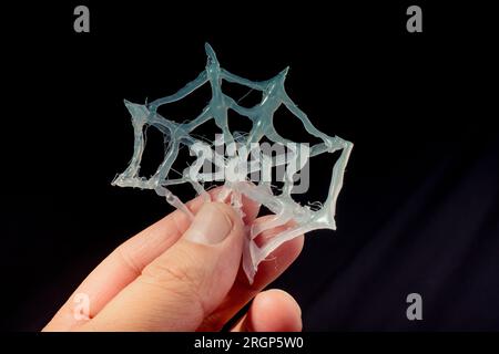 Fake spider web in hand on black background Stock Photo