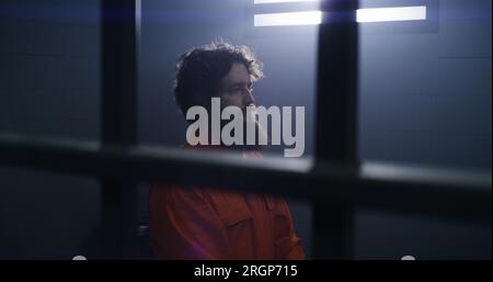 Believing Male Prisoner In Orange Uniform Kneels Near The Bed, Prays To 