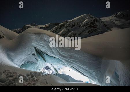Illuminated cave entrance in mountains, winter season Stock Photo