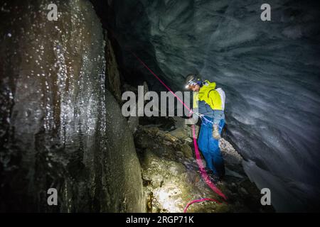 Climber and rescuer on safety rope inside glacial crevasse Stock Photo