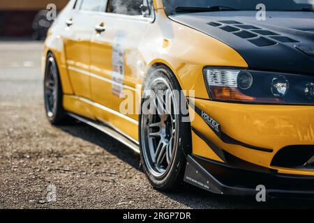 yellow Milsubishi Lancer Evo IX after few hot laps at local track event with smoke coming out of the front wheel arches. Stock Photo