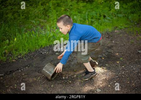 Child is holding dirty object. Little boy plays with concrete ring. Stock Photo