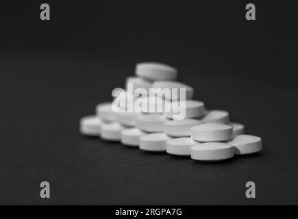 White tablets close-up on a black background with copy space. The concept of protecting the body from bacteria viruses Stock Photo