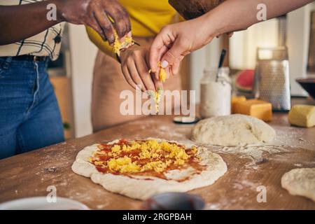 Hands, cheese and pizza for cooking, together and ready for fast food, restaurant or helping with skill in Naples. Chef woman, dough and tomato sauce Stock Photo