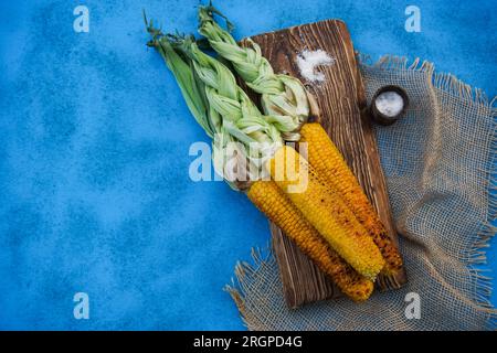On the blue table is grilled ripe yellow corn. High quality photo Stock Photo