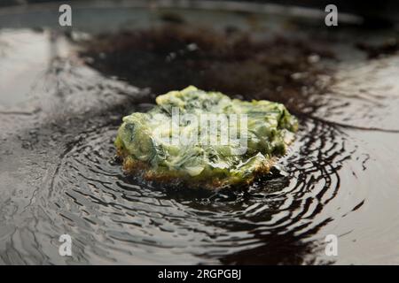 Pan cooking a spinach omelette at a street food stall on the streets of Bangkok, Thailand. Stock Photo