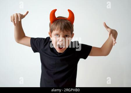 Halloween concept. cute little boy with red devil horns and pumpkin isolated on white background. Stock Photo