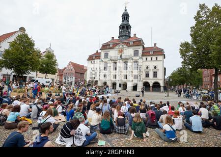 11 August 2023, Lower Saxony, Lüneburg: The participants of the protest march of the climate movement Fridays for Future have gathered in front of the town hall on the market square. The demonstration through Lüneburg is intended, among other things, to draw attention to the need for the new Hamburg-Hanover rail line. Photo: Georg Wendt/dpa Stock Photo