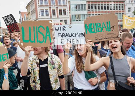 11 August 2023, Lower Saxony, Lüneburg: Participants of a protest march of the climate movement Fridays for Future carry cardboard signs with the inscriptions 'Luisa', 'we need one' and 'Neubauer'. The demonstration through Lüneburg is intended, among other things, to draw attention to the need for the new Hamburg-Hanover rail line. Photo: Georg Wendt/dpa Stock Photo