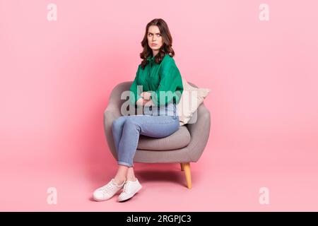 Full size photo of disappointed offended girl sir chair crossed arms look empty space isolated on pink color background Stock Photo