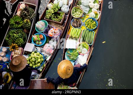 Women selling vegetables and fruit from their canoes at the Tha Kha floating market in Thailand. Stock Photo