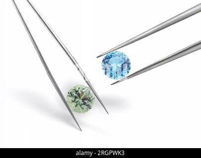 Large Blue and Green Gemstones Held in Tweezers Isolated on White Background Stock Photo