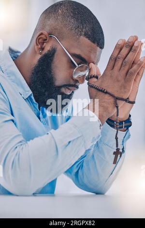 black man praying to god with cross and hands together Caribbean man ...