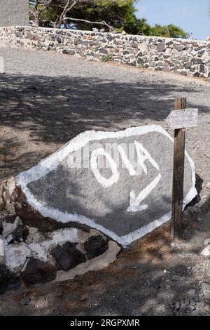 Photograph of the word 'OIA' and an arrow pointing left, painted on a large stone at the side of a road. Stock Photo
