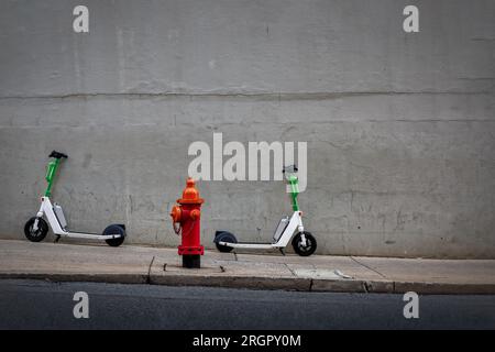 A sidewalk on a hill, with two scooters parked next to a fire hydrant, in Nashville, Tennessee. Stock Photo