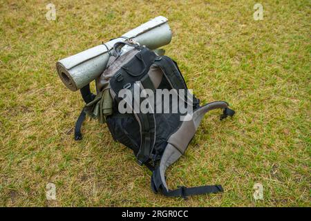 Big hiking backpack with a rolled sleeping mat laying on grass Stock Photo
