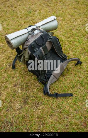 Big hiking backpack with a rolled sleeping mat laying on grass Stock Photo