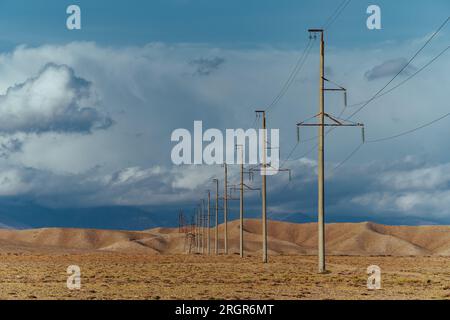 Electric power lines in field on mountains background Stock Photo