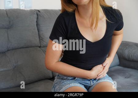 Beautiful young woman suffering from pain in her side at home Stock Photo