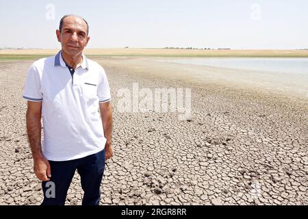 Diyarbakir, Turkey. 10th Aug, 2023. Dicle University Faculty of Science Biology Department Head Prof. Dr. Ahmet Kilic stands on cracked-mud surface at Kabakli lake, whose waters are withdrawn from the extreme heat. Kabakli lake, near the city of Diyarbakir in Turkey, where hundreds of birds are sheltering, is drying up due to the effective extreme temperatures. When the waters of the lake receded about 150 meters in the last month, wild birds began to leave the area. Dicle University Faculty of Science Biology Department Head Prof. Dr. Ahmet Kilic said that there are few birds left in the lak Stock Photo