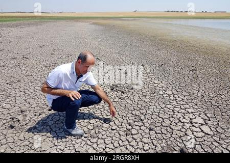 Diyarbakir, Turkey. 10th Aug, 2023. Dicle University Faculty of Science Biology Department Head Prof. Dr. Ahmet Kilic observes cracked-mud surface at Kabakli lake, whose waters are withdrawn from the extreme heat. Kabakli lake, near the city of Diyarbakir in Turkey, where hundreds of birds are sheltering, is drying up due to the effective extreme temperatures. When the waters of the lake receded about 150 meters in the last month, wild birds began to leave the area. Dicle University Faculty of Science Biology Department Head Prof. Dr. Ahmet Kilic said that there are few birds left in the lake Stock Photo