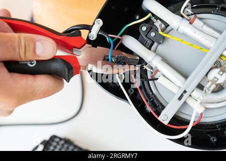 Repair of small household appliances, pliers in the hands of the master. Home repair service. Repair shop Stock Photo