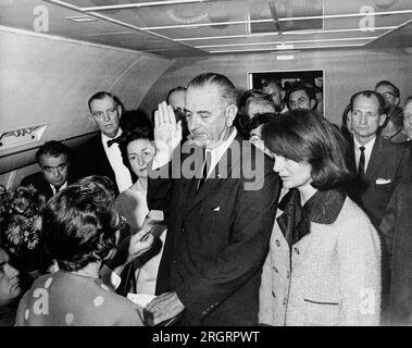 Dallas, Texas: November 22, 1963 Lyndon B. Johnson taking the oath of office on Air Force One at Love Field Airport two hours and eight minutes after the assassination of John F. Kennedy. L-R: Mac Kilduff (holding dictating machine), Judge Sarah T. Hughes, Jack Valenti, Congressman Albert Thomas, Marie Fehmer (behind Thomas), First Lady Lady Bird Johnson, Dallas Police Chief Jesse Curry, President Lyndon B. Johnson, Evelyn Lincoln (eyeglasses only visible above LBJ's shoulder), Congressman Homer Thornberry (in shadow, partially obscured by LBJ), Roy Kellerman (partially obscured by Thornberry) Stock Photo