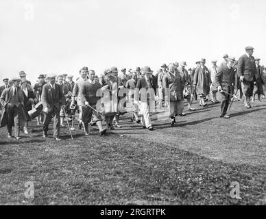 World:  c. 1926 Bobby Jones walking on a golf course followed by his gallery. Stock Photo