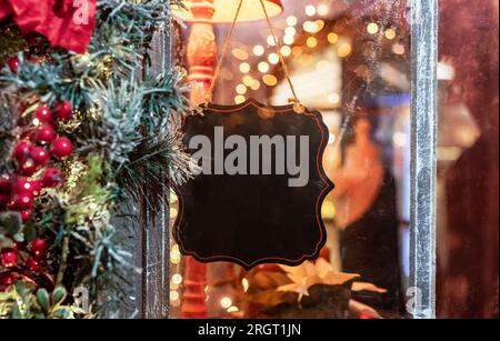 Empty blank black signboard, sign board hanging on cafe or shop window, decorated for Christmas holiday. Stock Photo