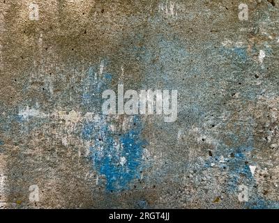 The texture of an old concrete wall, painted over with strokes of light brown and blue paint for background and design. Photo Stock Photo