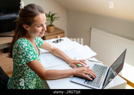 Young adult woman studying online on the Internet using her laptop for the e-learning, online courses and educational training. Stock Photo