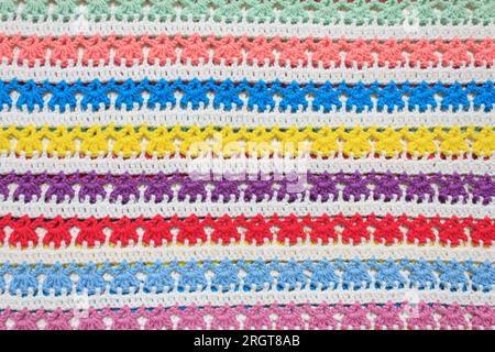 Background crocheted fabric, pattern of multi-colored rows handmade. Stock Photo