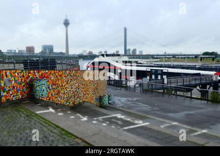 Famous Rhine Stairs in Düsseldorf. They are empty on a rainy day. These stairs connect the quay with the promenade. A tour boat is moored. The TV towe Stock Photo