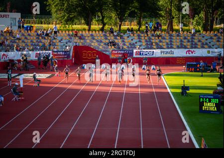 B. BYSTRICA, SLOVAKIA, JULY 20, 2023: Female Sprinters Navigate 100m Race with Grace in Enchanting Twilight Setting at Track and Field Meet for Worlds Stock Photo