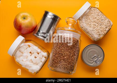 Donations food with canned food on yellow table background Stock Photo