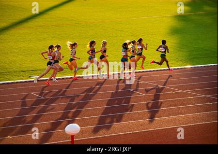 B. BYSTRICA, SLOVAKIA, JULY 20, 2023: Female Sprinters Compete in 800m Race Amidst Stunning Sunset Lighting at Track and Field Championship for Worlds Stock Photo