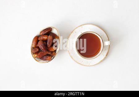 Tea and dried dates on white background. Natural oriental sweets. Healthy breakfast. View from above. Stock Photo