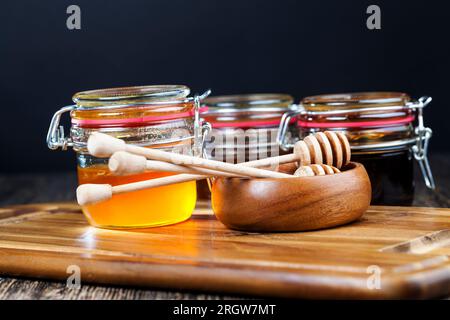 several varieties of honey from different varieties of flower plants, bottled in different jars several different types of honey that differ in color, Stock Photo