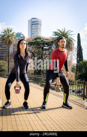 Man and woman exercising with dumbbells during a workout in the park. Stock Photo
