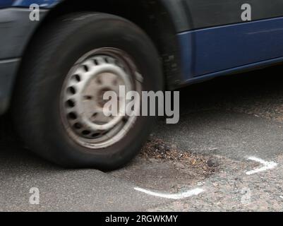 File photo dated 11/5/2018 of a car hitting a pothole on a road. UK cuts to spending on tackling potholes are among the most severe out of 13 major nations, according to new analysis. Annual expenditure on local roads maintenance in the UK fell from £4 billion in 2006 to £2 billion in 2019, which was the last year of international comparable data available. Issue date: Saturday August 12, 2023. Stock Photo