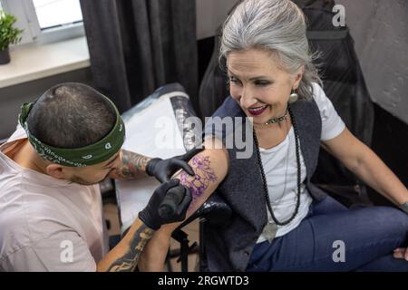 Male tattoo master working in the salon with a customer Stock Photo