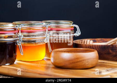 several varieties of honey from different varieties of flower plants, bottled in different jars several different types of honey that differ in color, Stock Photo