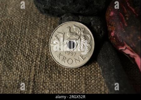 1 Krone Harald V 1997 reverse. Norwegian coin and stones on natural linen fabric. Business and finance. Stock Photo