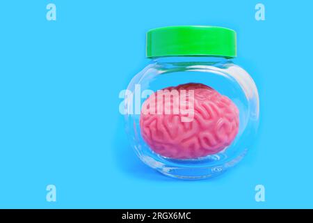 Close-up of a miniature human brain replica preserved in a glass jar. Halloween or horror related concept. Stock Photo