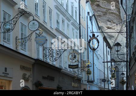Old, traditional, Wrought Iron signs hanging above shops on The Getreidegasse - a famous shopping street in the old town of Salzburg Stock Photo