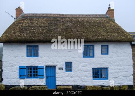 Capslan cottage, with white painted stone exterior and thatched roof is a Grade II listed building in Sennen Cove, Cornwall. Stock Photo