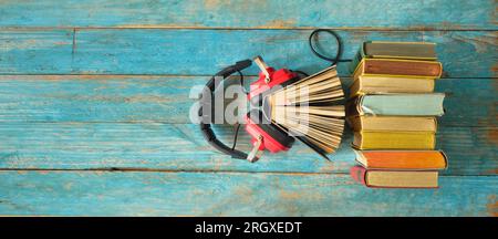 audio book concept with row of books and vintage red headphones,flat lay on blue wooden planks, free copy space Stock Photo