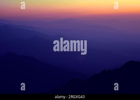 Silhouettes of mountain ranges in the evening haze. Twilight Stock Photo