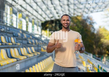 Portrait of sportsman with bottle of water, man resting walking stadium for training, young athlete yoga and fitness trainer. Stock Photo