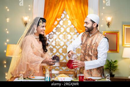 Happy indian couple arranging ramadan feast or food preparing by talking together at home - concept of relationship, festival celebration and Ramzan Stock Photo
